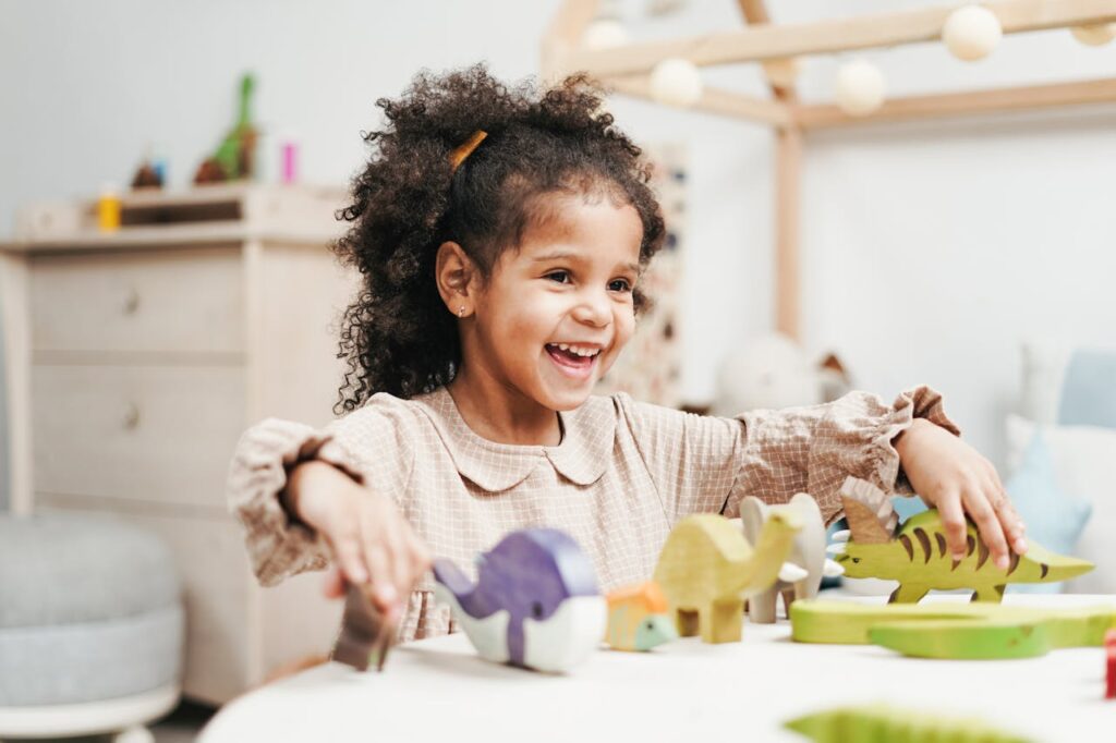 selective-focus-photo-of-laughing-young-girl-playing-with-wooden-toys-on-white-table